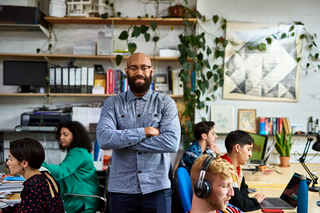 Happy man standing around students on their computers